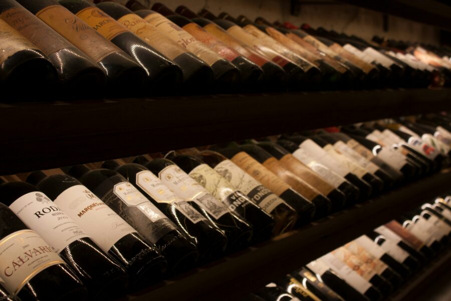 Garrafas de vinho tinto em prateleira de adega